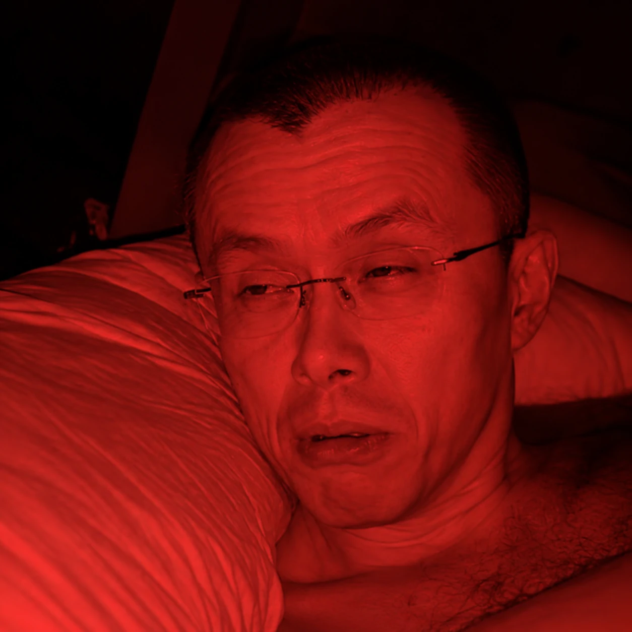 Red-lit portrait of Red Morning awake in bed